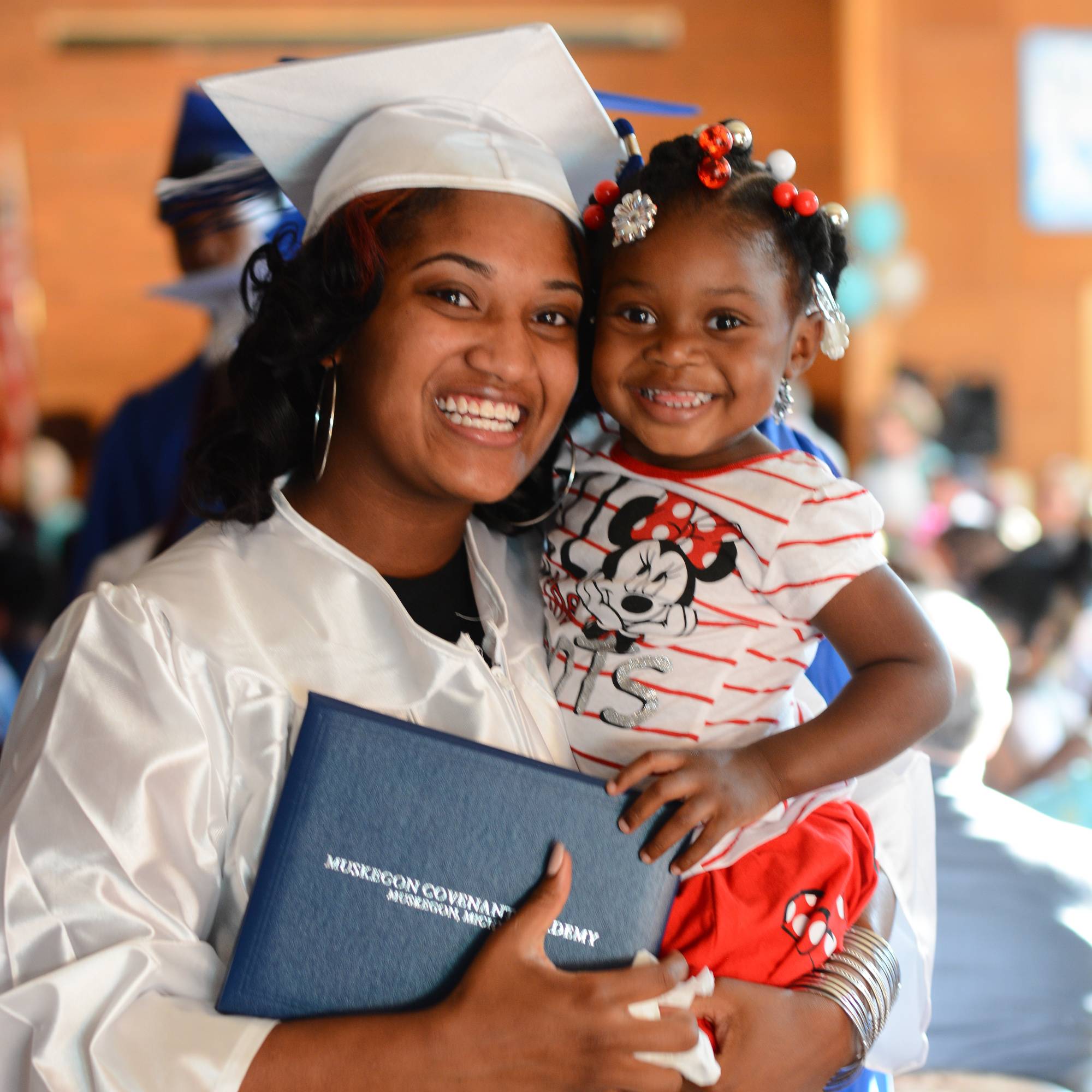 Graduating student holding diploma and young child